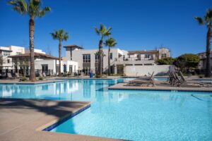 Luxury swim club at Playa Del Sol featuring a large sparkling pool, spa, and poolside lounge chairs