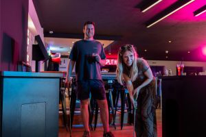 People enjoying interactive entertainment playing a game of mini golf