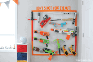 Colorful toy guns and tools displayed on a pegboard with the phrase