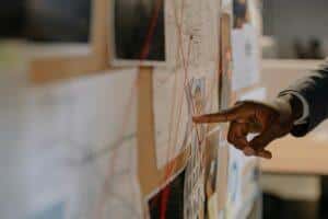 Home 14 Close-up of an investigator pointing at an evidence board with connected clues using red strings.