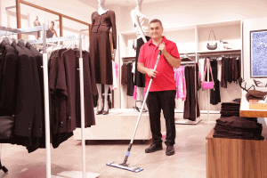 AMC cleaner in uniform cleaning the floor ar high fashion retail store in shopping centre