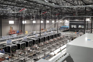 A row of apple packers in a packhouse. - Photo: Robotics Plus