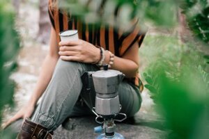 person in grey pants sitting beside grey metal kettle 3621593