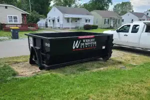 A black wright dumpster rental container placed in a residential area