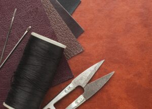 Lederstücke, Nadel, Faden und Schneidwerkzeug als Symbol für einen sexpositiven Workshop zum Flogger selber machen in Stuttgart.