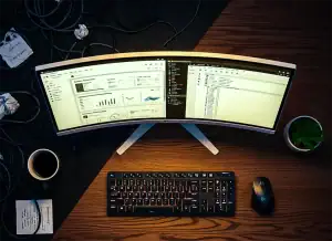 Mesa com setup minimalista com teclado sem fio e monitor Ultra Wide em um escritório