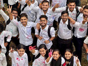 A vibrant group of college students celebrating outdoors with cheerful expressions and white shirts signed with colorful inks.