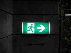 A white and green exit sign on the wall, a visual metaphor for moving forward through PTSD therapy in Michigan.