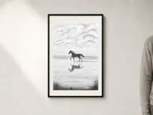Disegno in carboncino di un cavallo libero che corre sulla battigia, con il riflesso nell’acqua lasciata dall’onda appena ritirata, uccelli e cielo nuvoloso sullo sfondo; passepartout e cornice nera, dimensioni esterne 52 × 72 cm.