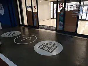 Segnaletica orizzontale in resina nell'area di accoglienza di un centro commerciale GDO, percorsi pedonali e indicazioni direzionali integrate nel pavimento