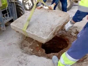 Operarios levantan una losa de piedra en las obras de la plaza de los Santos Niños de Alcalá de Henares