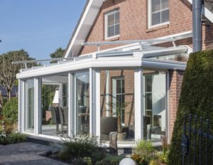 Senkrechter VaroSun Sonnenschutz, installiert an einem Fenster eines modernen Einfamilienhauses, bietet effektive Abschirmung vor direkter Sonneneinstrahlung und reduziert die Innentemperatur.