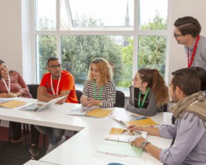 Internationale Sprachschüler lernen gemeinsam in einem modernen, lichtdurchfluteten Klassenzimmer.