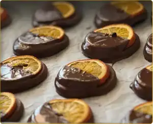 Orangettes confites enrobées de chocolat noir, décorées de rondelles d’orange séchée.