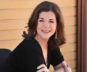 Renae Ingraham wearing long earrings and a black shirt smiling