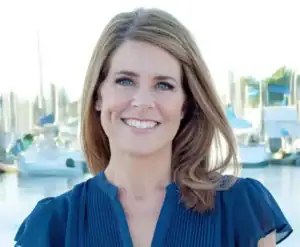 rita blair wearing a blue button down shirt standing in front of the marina