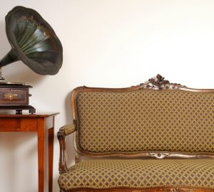 mobili vintage; piccolo divano vintage a due posti, piccolo mobiletto rosso e giradischi con grammofono