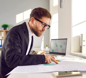 DOCFA, uomo a lavoro con documenti catastali e pc