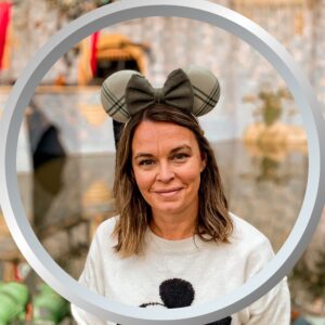 Festive woman wearing Disney-inspired ears at Disney theme park, enjoying her vacation.
