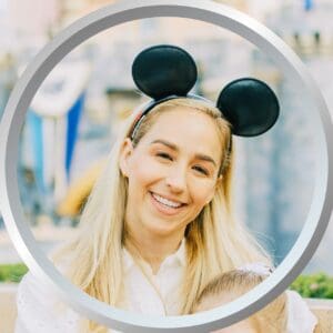 Happy woman wearing Disney Mickey Mouse ears at a theme park, enjoying a magical vacation experience.