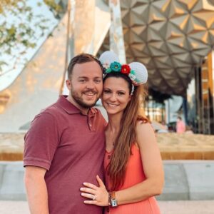 Cute couple at Epcot with park icon in background, enjoying a Disney vacation.