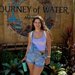 Vibrant woman enjoying Florida vacation at 407 Vacations, surrounded by lush tropical plants and scenic Water Journey backdrop.