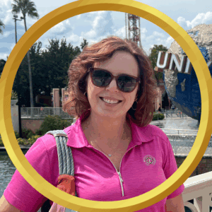 Smiling woman in pink shirt at Universal Studios Orlando themed park.