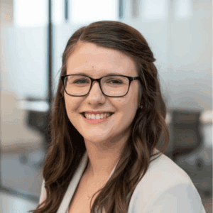 Professional woman wearing glasses smiling in an office setting.