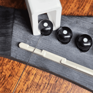 Guitar string winder in white removing bridge pins from acoustic guitar