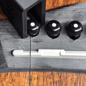 Guitar string winder in black removing bridge pins from acoustic guitar