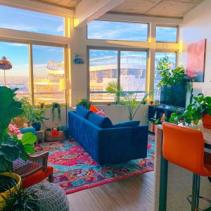 Modern apartment living room with a blue couch surrounded by lush greenery and stylish design accents showcasing contemporary apartment decor ideas for small spaces.