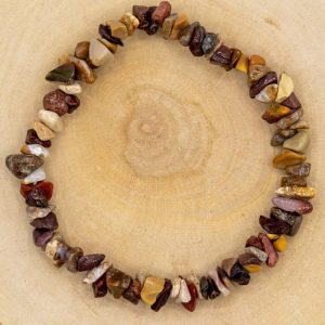 Mookaite Jasper Chip Stretch Bracelet, a beaded accessory made of multicolored natural Mookaite Jasper chips arranged in a stretch bracelet design on a wooden surface.