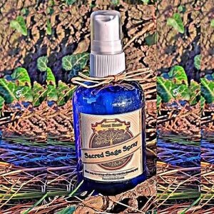 Sage Clearing Spray – 4 oz Organic Mt. Shasta Sage 'Liquid Smudge', blue glass bottle with white spray cap and natural twine, placed outdoors on natural ground with green plants and soil background.