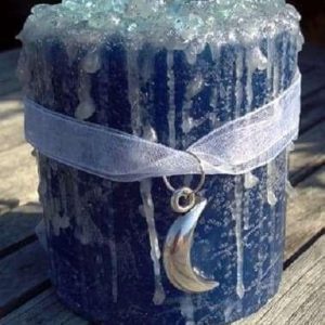 Blue Moon Candle, a large blue candle with a textured surface and a crescent moon pendant necklace wrapped around it.