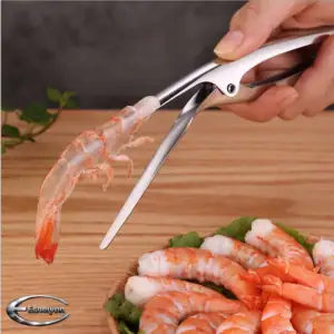 Stainless steel seafood peeler deveiner being used to peel and devein a prawn, showing clean shell removal and prepared prawns on a kitchen surface.