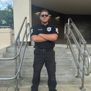 Uniformed security officer standing with arms crossed at a building entrance