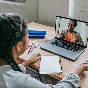 ethnic girl having video chat with teacher online on laptop