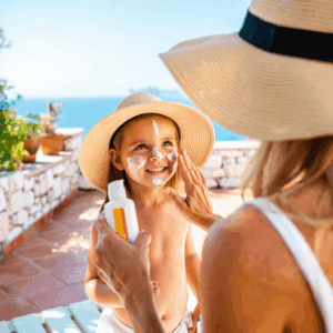 Madre aplicando crema solar a su hija en una terraza familiar durante el verano