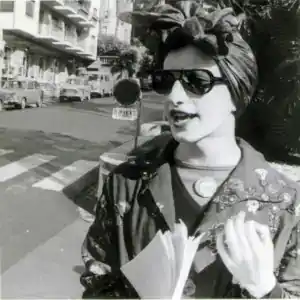 Mario Mieli a Sanremo il 5 aprile 1972, con turbante, occhiali scuri e la spilletta del Gay Liberation Front