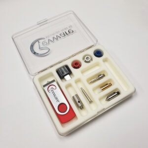 A small clear box on white background with the lid open and a white foam insert showing MicroScribe probe tips and USB drive.