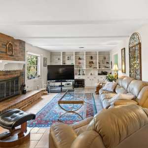 Cozy living room with leather sofas, brick fireplace, and built-in white shelving filled with decor, perfect for relaxation and family gatherings.