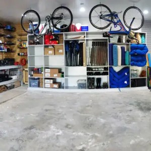 Bicycle and outdoor gear storage in a well-organized garage or shop space with shelving for outdoor equipment and accessories.