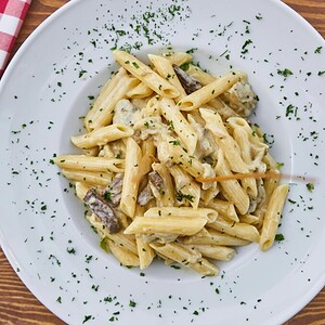 pexels photo 1487511 1487511 1 Delicious creamy penne pasta with mushrooms and parsley on a rustic table setting.
