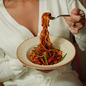 pexels photo 19051899 19051899 A woman in a white outfit enjoying a delicious bowl of savory noodles indoors.