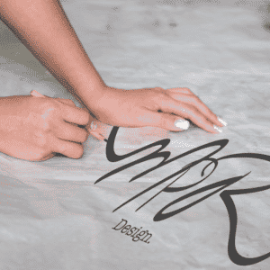 Hands smoothing paper with "MPR Design" logo. Vector tracing concept.