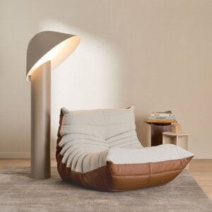 BOSS × Ligne Roset Togo fireside chair in grège textile and hazelnut leather beside the taupe Azores floor lamp.