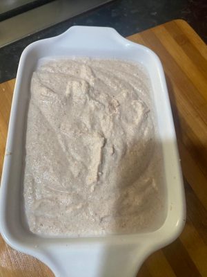 A bowl of creamy Chura Gerteh topped with fresh banana slices and colorful chopped fruits