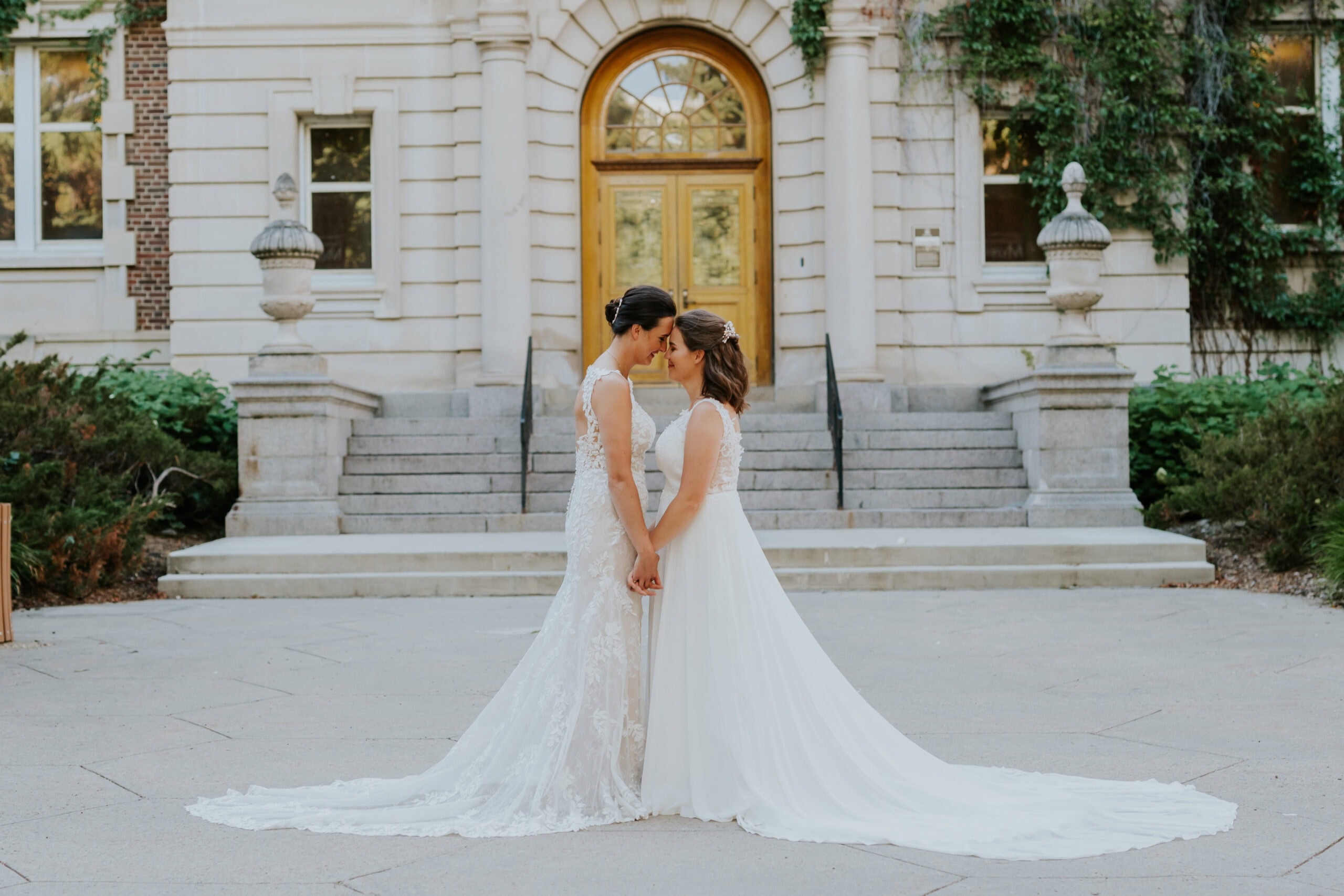 Wedding Photography - two brides holding hands in front of a staircase outoors