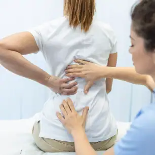 Physical therapist assessing back pain and mobility before surgery preparation