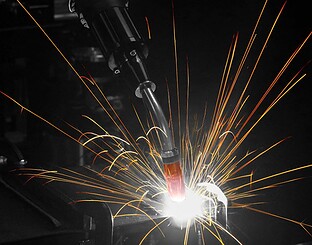 Closeup of robotic MIG welding gun with sparks